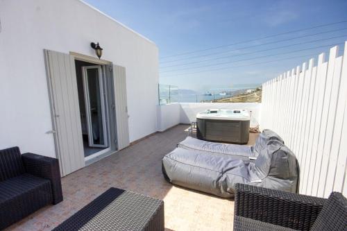 a living room with a couch and a tv on a balcony at Anixi - Primavera Mykonos in Ornos