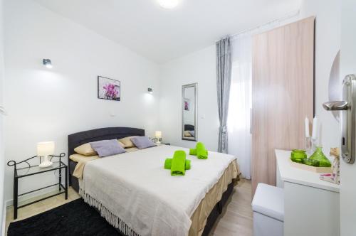 a bedroom with a large bed with green chairs on it at Apartments Maraš in Zadar