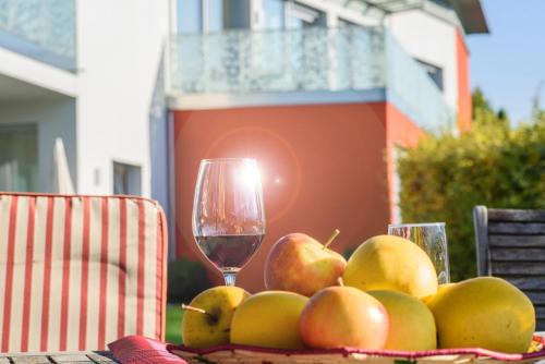 a plate of apples and a glass of wine on a table at Arboris Appartement in Appiano sulla Strada del Vino