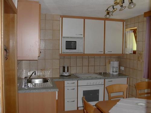 a kitchen with white cabinets and a sink and a table at Haus Michael in Oetz