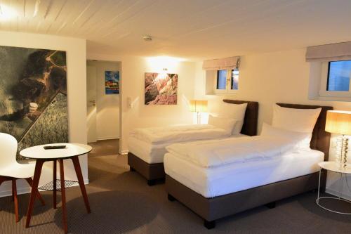 um quarto de hotel com duas camas e uma mesa em Haus Sathurn em Helgoland