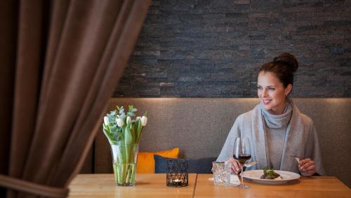 a woman sitting at a table with a glass of wine at Vuokatin Aateli Apartments in Vuokatti