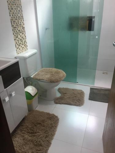 y baño con aseo, ducha y 2 alfombras. en Casa Aconchego cataratas, en Foz do Iguaçu
