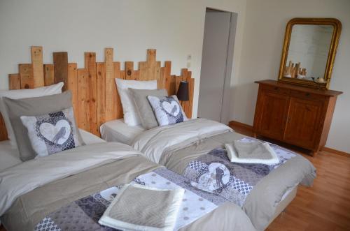 1 dormitorio con 2 camas, toallas y espejo en Gîte Brin de Campagne, en Vaucremont