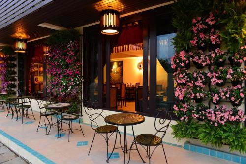 a group of tables and chairs in front of a building with flowers at Kongkam House in Mae Sai