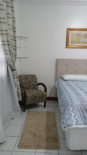 a bedroom with a bed and a chair at London House in São José