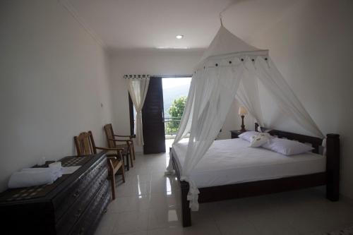 a bedroom with a bed with a mosquito net at Dangin Mangkalan Homestay in Munduk