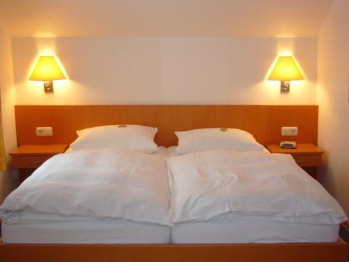 a bed with two white pillows and two lamps at Hotel Deutsches Haus in Kaub