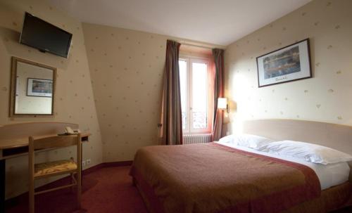 a hotel room with a bed and a desk and a window at Hôtel Transcontinental in Paris