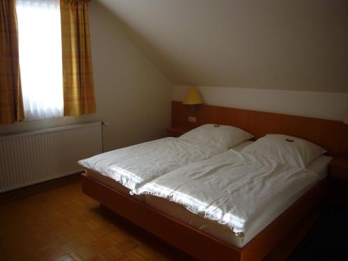 a bedroom with a bed with white sheets and a window at Hotel Deutsches Haus in Kaub