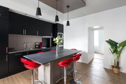 une cuisine avec des placards noirs et des tabourets de bar rouges dans l'établissement Zen et design, proche Cité Corsaire, à Saint-Malo