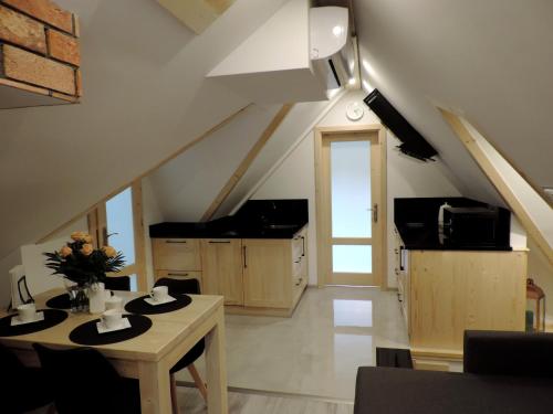 an attic room with a table and a kitchen at Na Świerkowym Strychu in Szczawnica