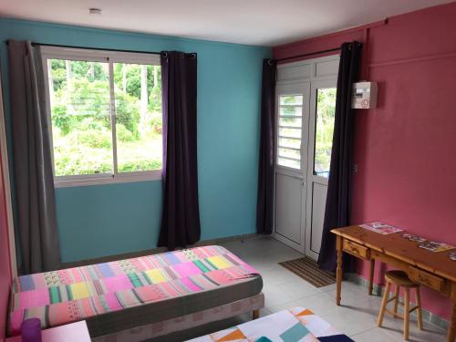 a room with a bed and a table and windows at L'Escale du Mouillage in Saint-Pierre