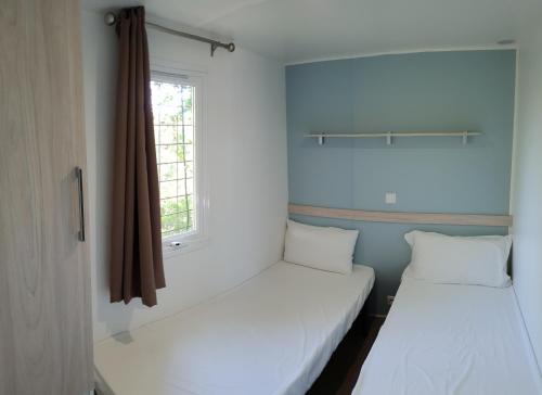 2 camas en una habitación pequeña con ventana en Camping Coll Vert, en Pinedo