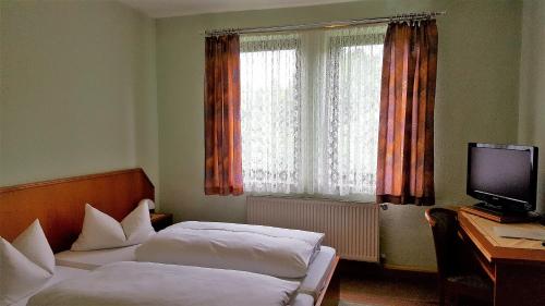 a bedroom with two beds and a desk and a television at Pension Waldfrieden in Wolkenstein