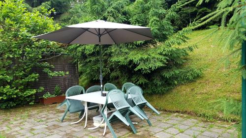 a table and chairs with an umbrella on a patio at Pension Waldfrieden in Wolkenstein