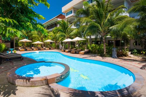 una piscina en un complejo con palmeras y sombrillas en Simple Life Resort Koh Tao, en Ko Tao