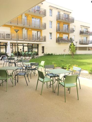 a group of tables and chairs in front of a building at Domitys Rosa Gallica in Angers