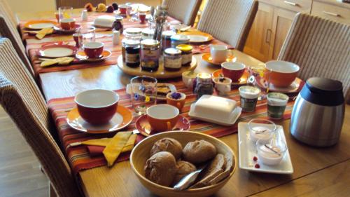 a table with food and cups and plates of food at Ökopension Villa Weissig in Struppen