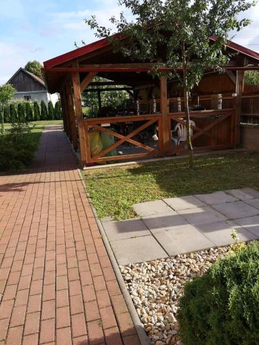 a wooden pavilion with a tree in a garden at Apartmany-Anna in Podhájska