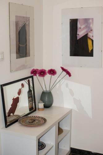 a table with a vase with purple flowers on it at B&B Myrta Maria in Cagliari