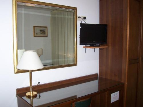 Habitación con TV, lámpara y espejo. en Hotel Caldin's en Chioggia