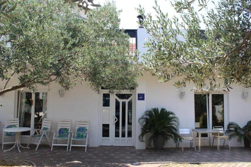a white building with chairs and tables and trees at Pansion Ana in Podaca