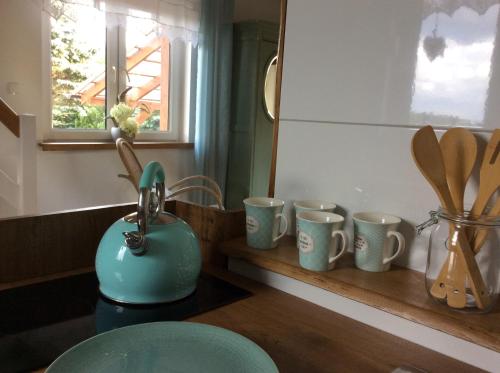 a kitchen counter with a row of mugs on a shelf at Lemon home in Dziemiany