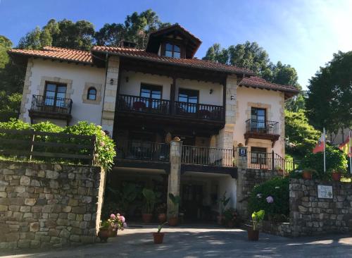 una grande casa con balconi su un muro di pietra di Posada Fuentedevilla a Pechón
