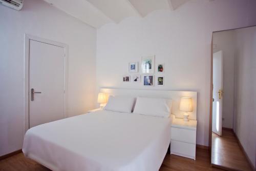 een witte slaapkamer met een wit bed en 2 lampen bij Ramblas Apartments in Barcelona