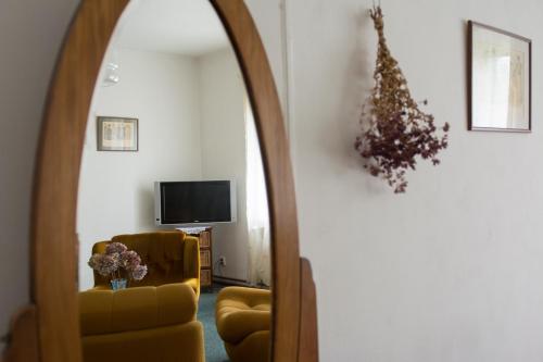 a living room with a yellow chair and a mirror at Penzion Signum Laudis in Velké Hamry