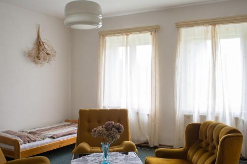 a living room with a table and chairs and a bed at Penzion Signum Laudis in Velké Hamry