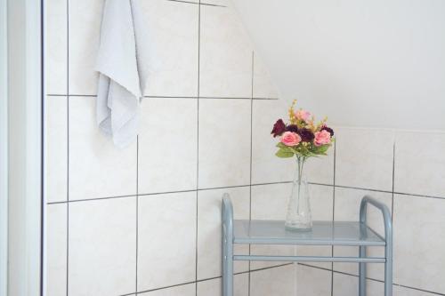 a vase of flowers on a table in a bathroom at Penzion Signum Laudis in Velké Hamry