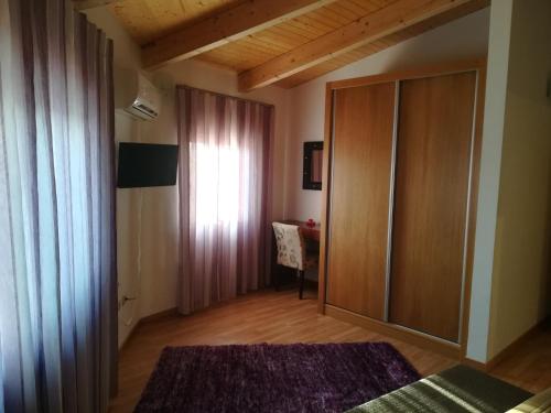 a bedroom with a closet and a window and a desk at Casa do Azibo in Santa Combinha