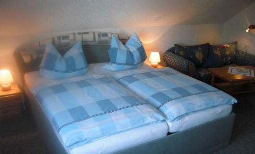 ein Schlafzimmer mit einem Bett mit blauer Bettwäsche und einem Sofa in der Unterkunft Ferienwohnung Windten in Braunlage