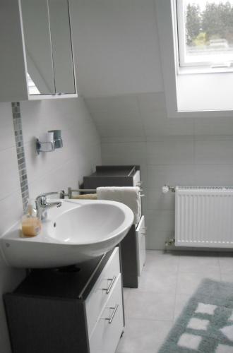 a white bathroom with a sink and a window at Ferienwohnung Windten in Braunlage