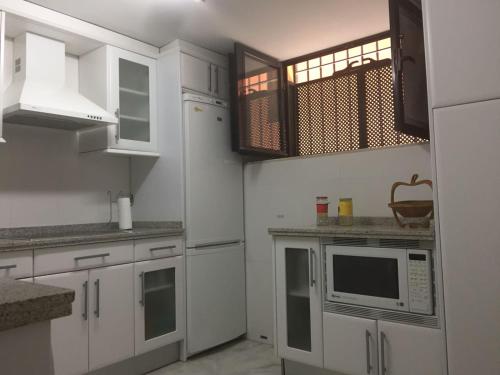cocina con armarios blancos y microondas en Apartamento duplex en centro de Sevilla, en Sevilla