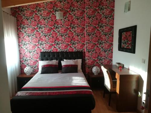 a bedroom with a bed with a red floral wallpaper at Casa do Azibo in Santa Combinha
