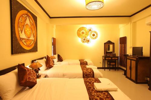 a hotel room with three beds and a television at Kongkam House in Mae Sai