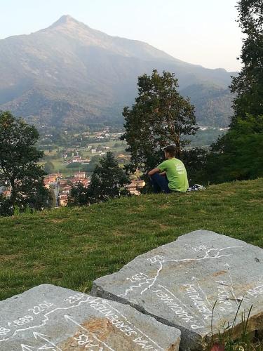 a man sitting on a hill looking at a mountain at Cascina La Commenda in Peveragno