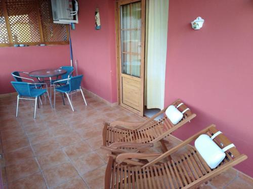 a room with a table and chairs and a pink wall at Apartamentos La Banda in Playa de Santiago