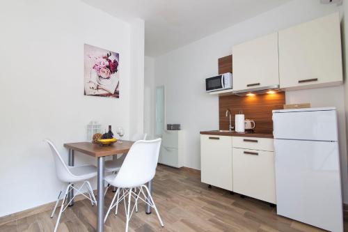 cocina con armarios blancos, mesa y sillas en Apartment Francesco, en Šibenik