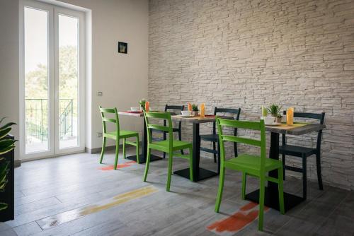 un comedor con sillas y mesas verdes y una pared de ladrillo en L'Agrumeto, en Procida