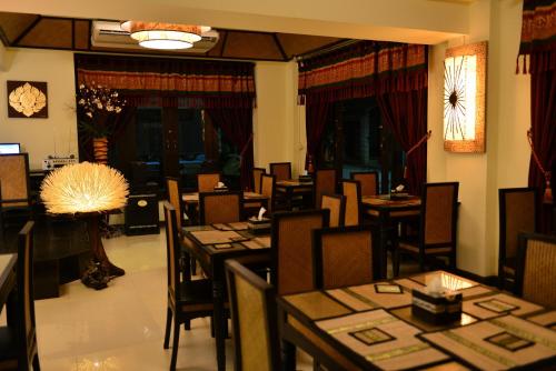 uma sala de jantar com mesas e cadeiras e um candeeiro em Kongkam House em Mae Sai
