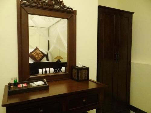 a mirror on top of a wooden dresser in a room at Kongkam House in Mae Sai