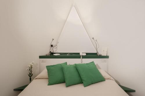 a bed with two green pillows on top of it at Edificio 15 House Elite in Rodi Garganico