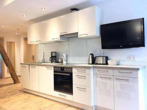 a kitchen with white cabinets and a flat screen tv at Hotel Garni Grünmoos in Sankt Jakob in Defereggen