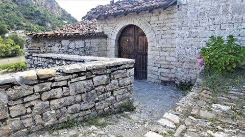 a stone building with a wooden door and a stone wall at Dhimitri's guest house in Berat