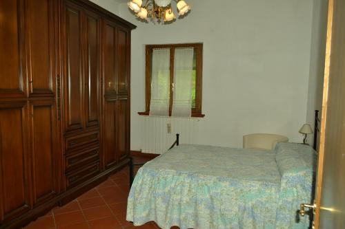 - une chambre avec un lit, des armoires en bois et une fenêtre dans l'établissement Appartamenti La Miniera, à Castelnuovo Berardenga