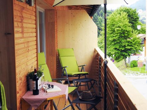 a balcony with green chairs and a table and an umbrella at Leos Alpenblume inklusive Sommer Bergbahnticket in Oberstdorf